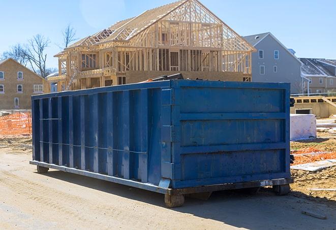 a small bulldozer dumping a pile of debris into a residential dumpster